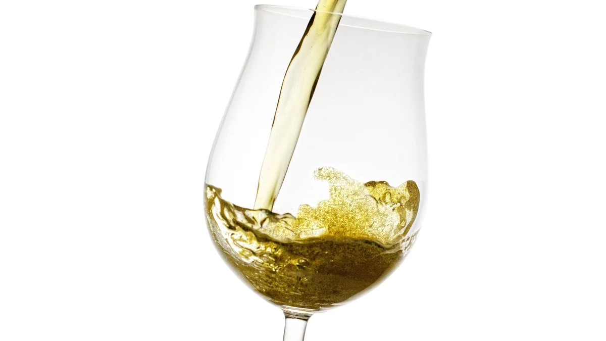 Goudgele zoete witte wijn wordt ingeschonken in een wijnglas